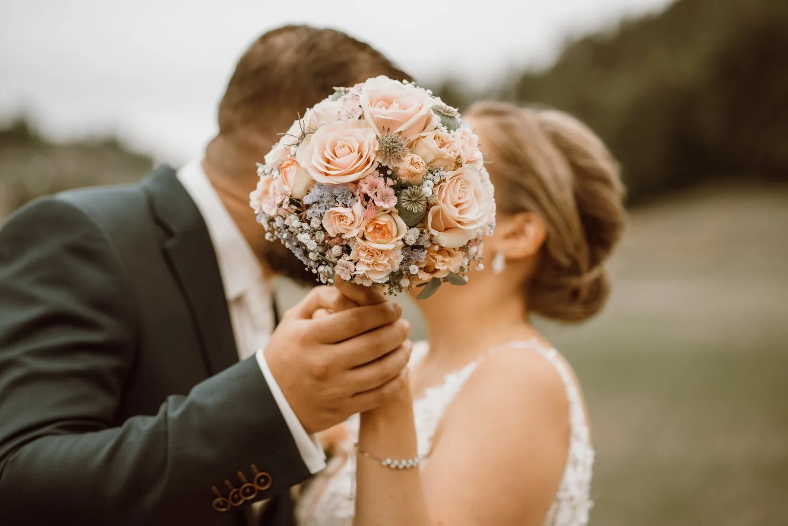 Brautpaar küsst sich hinter dem Brautstrauss – Hochzeitsfotograf Ostschweiz